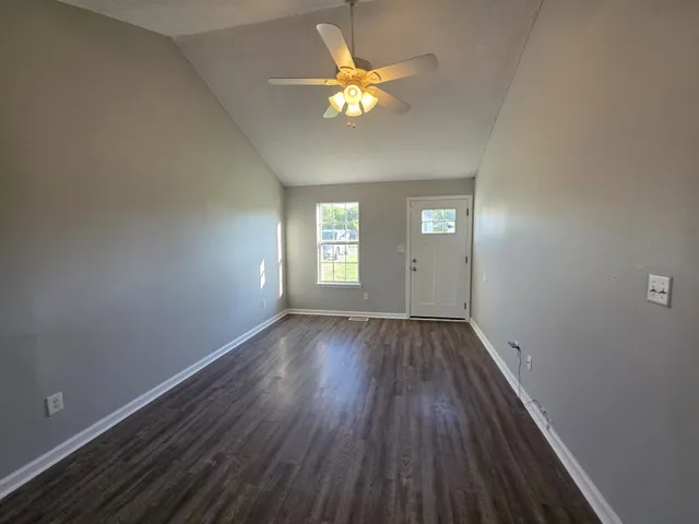 a view of an empty room with window and wooden floor
