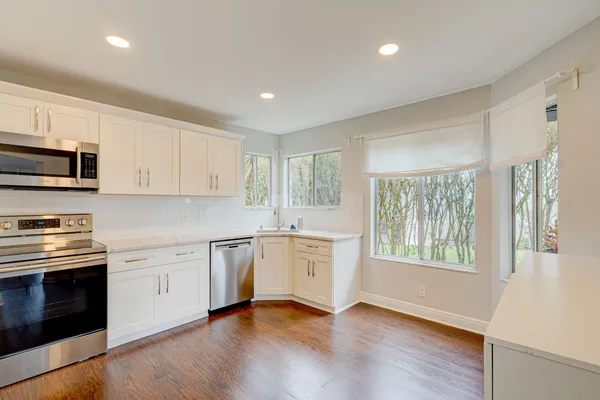 an empty room with wooden floor and windows