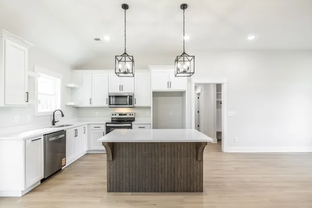 a large kitchen with stainless steel appliances granite countertop a stove a sink a refrigerator a center island a stove and a window