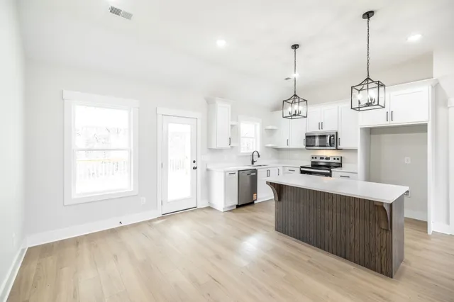 a large kitchen with kitchen island a stove a sink a center island and wooden floor