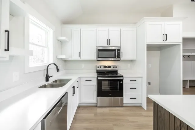 a kitchen with stainless steel appliances a stove sink microwave and cabinets