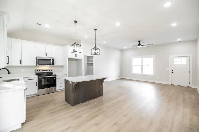 a kitchen with stainless steel appliances granite countertop a sink a stove and a wooden floors