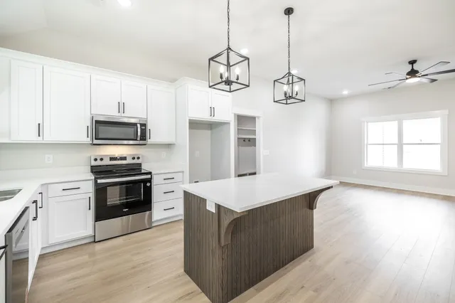 a kitchen with stainless steel appliances granite countertop a stove a sink and a wooden floor