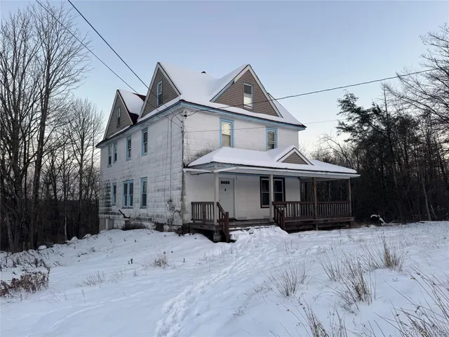 a view of a white house with a yard covered in snow