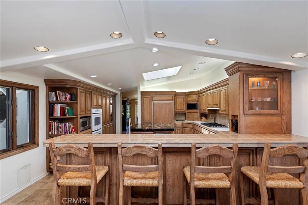 2100 Hathaway Place Riverside, CA 92506 - Photo 15 of 74 a kitchen with a table chairs a sink dishwasher refrigerator and cabinets