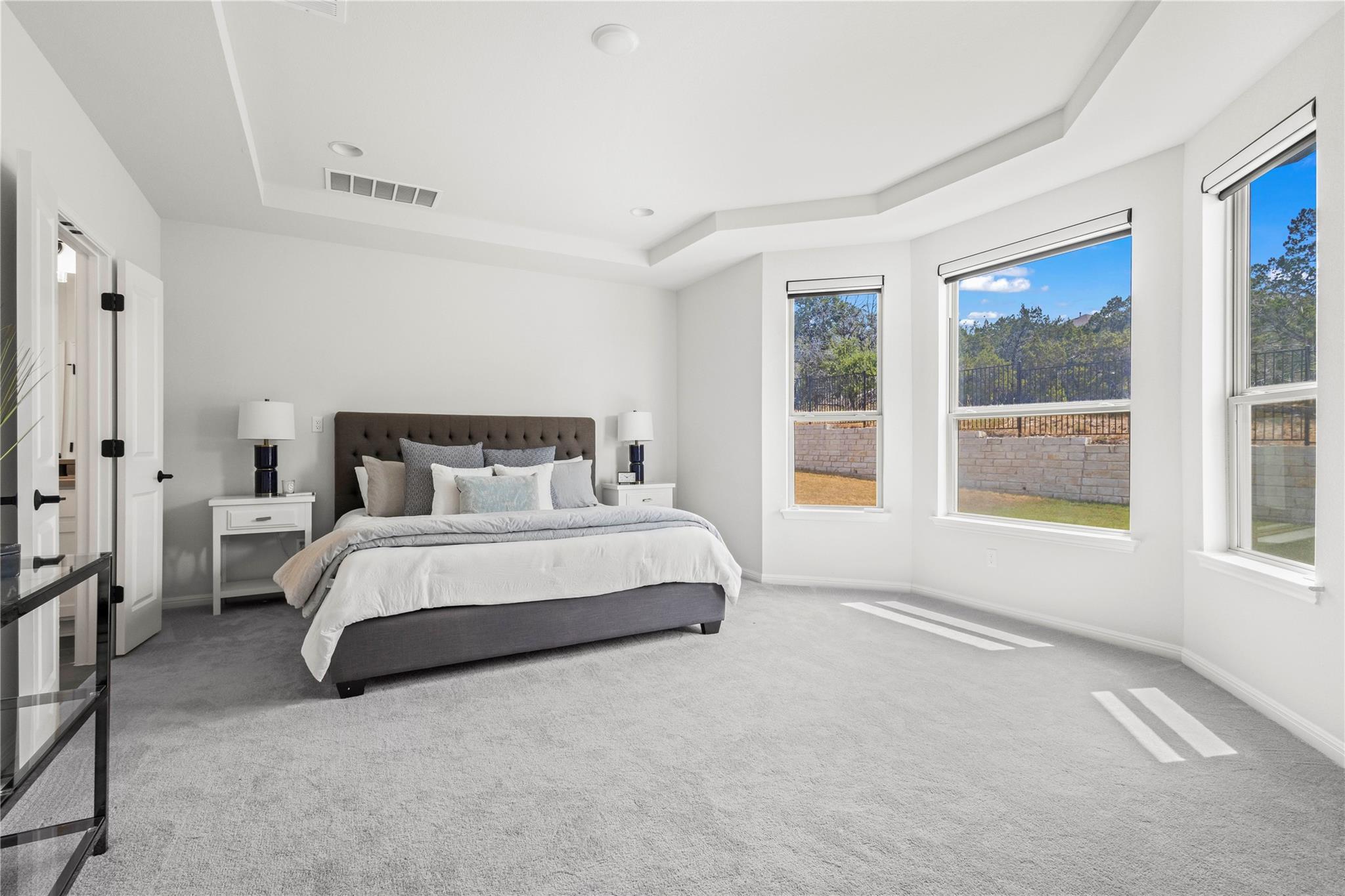 1128 Villa Rialto View Leander, TX 78641 - Photo 23 of 40 Natural light illuminates this spacious bedroom with tray ceilings and plush carpeting.