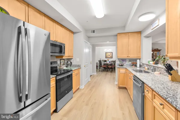 a large kitchen with granite countertop a large counter top stainless steel appliances a sink cabinets and a window