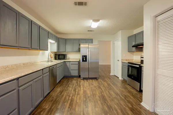 a kitchen with granite countertop a refrigerator and a stove top oven