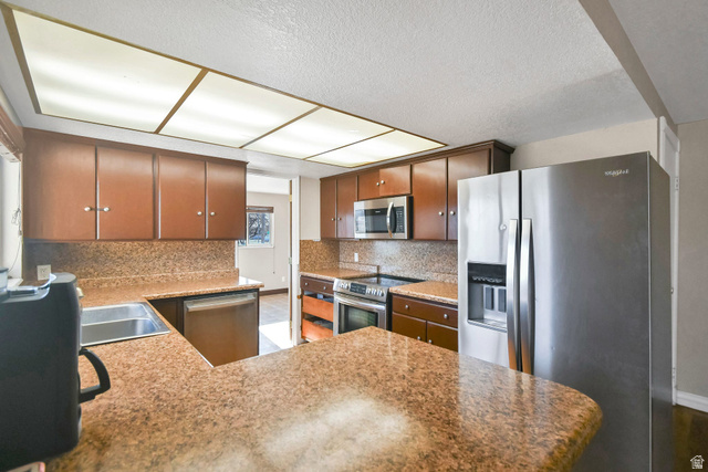 10 North Main Street Centerfield, UT 84622 - Photo 13 of 52 Kitchen featuring appliances with stainless steel finishes, tasteful backsplash, a textured ceiling, a peninsula, and light stone counters