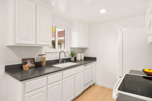 a kitchen with stainless steel appliances granite countertop a sink and a white cabinets