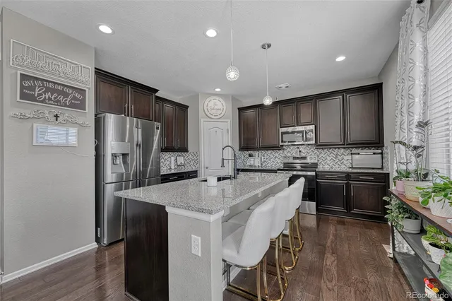 a kitchen with stainless steel appliances granite countertop a refrigerator a sink dishwasher a stove with wooden floors and cabinets