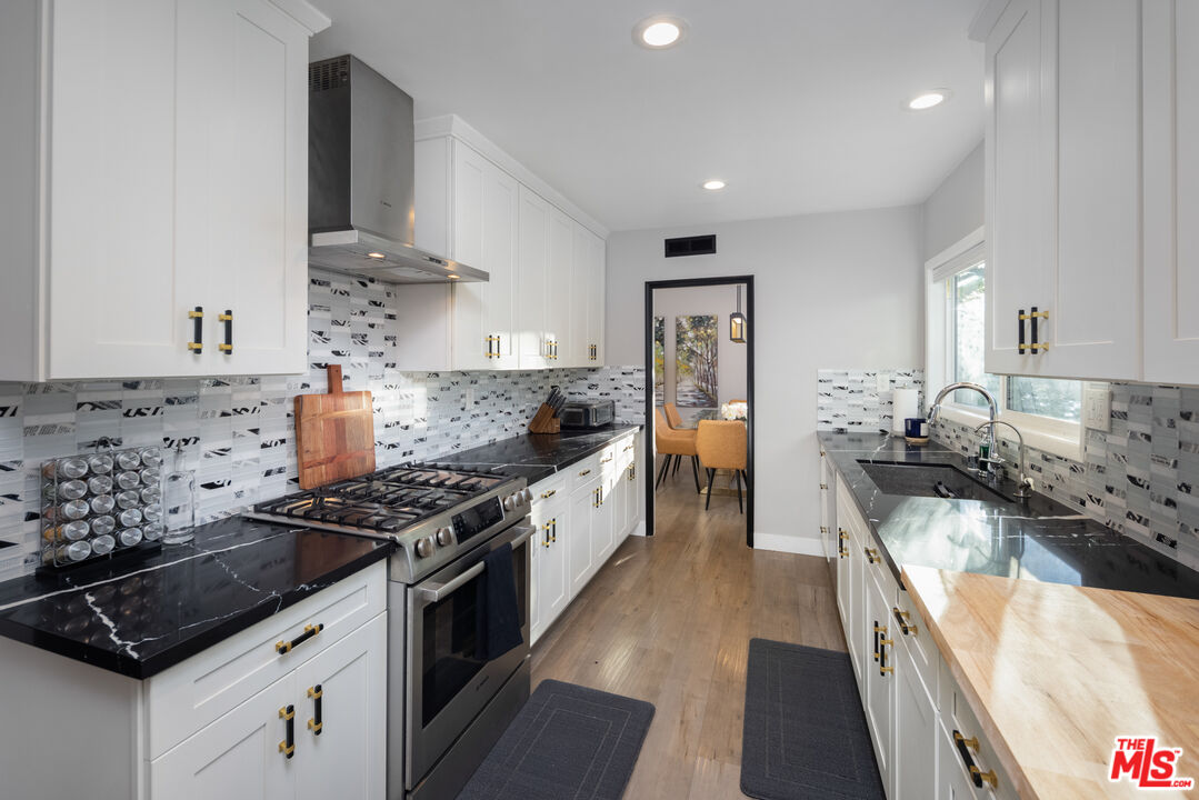 9476 Hidden Valley Place Beverly Hills, CA 90210 - Photo 4 of 43 a kitchen with stainless steel appliances a sink stove and cabinets
