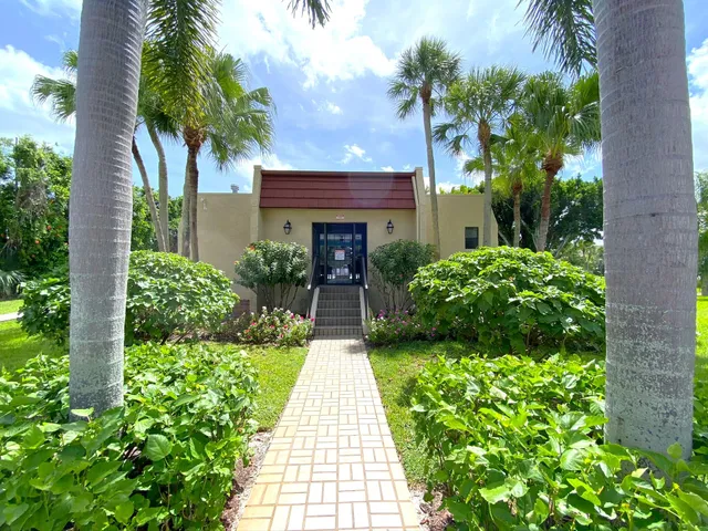 a front view of a house with a yard and potted plants