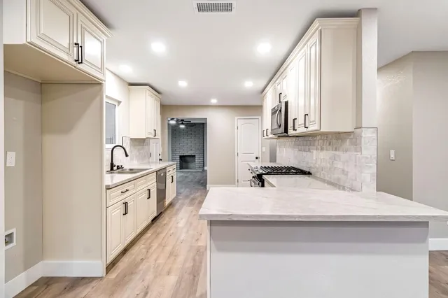 a kitchen with granite countertop a sink stainless steel appliances and cabinets