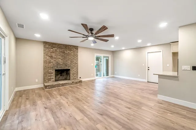 an empty room with wooden floor and a fireplace