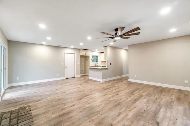 a view of an empty room with a ceiling fan and wooden floor