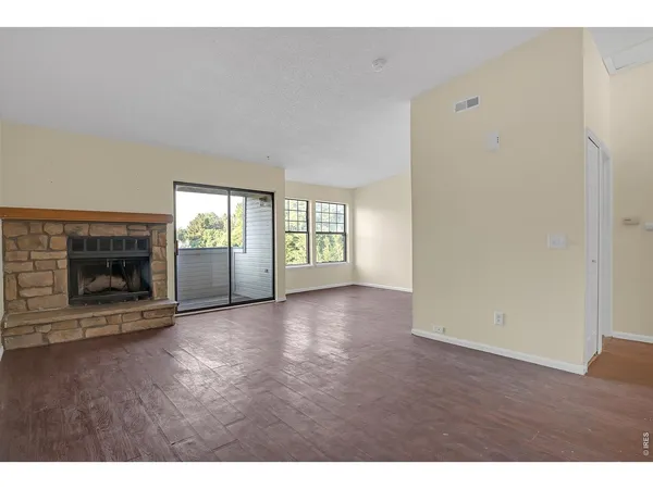a view of an empty room with a fireplace and a window