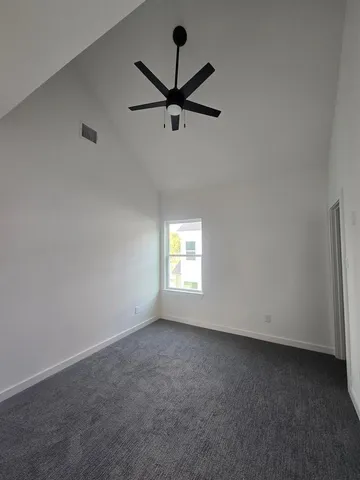 an empty room with ceiling fan and window