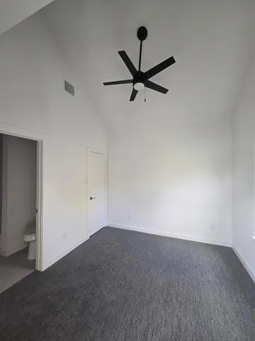 a view of a room with a ceiling fan and hardwood floor