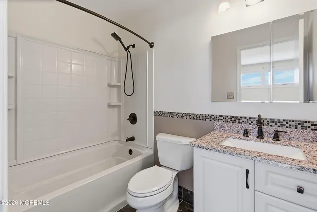 a bathroom with a granite countertop toilet a sink and a bathtub