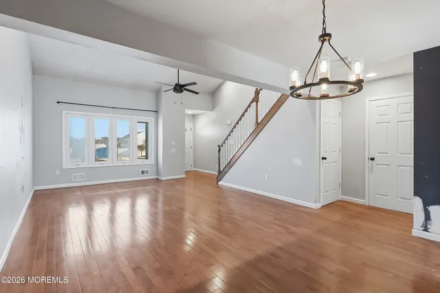 a view of an empty room with wooden floor entryway and a ceiling fan