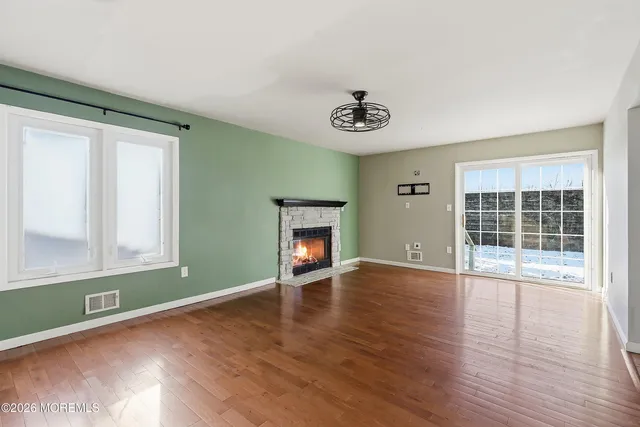 an empty room with wooden floor a ceiling fan and windows
