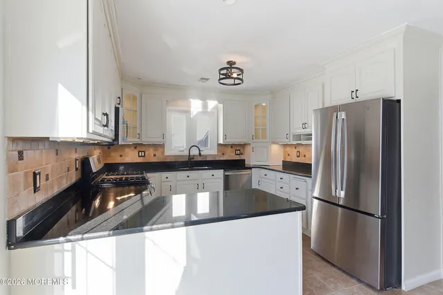 a kitchen with a refrigerator a sink and white cabinets