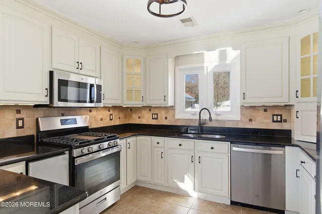 a kitchen with granite countertop white cabinets and appliances