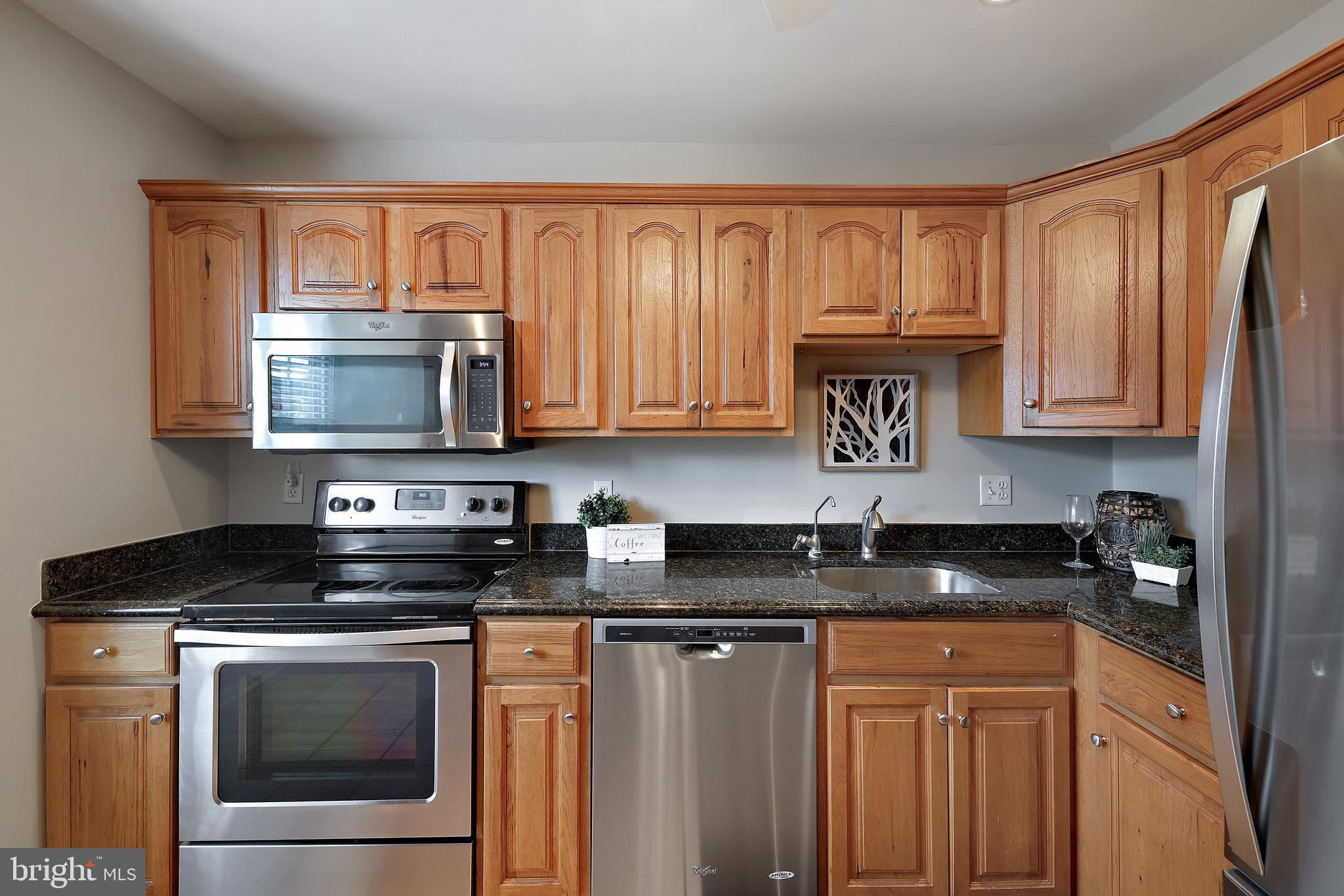a kitchen with stainless steel appliances granite countertop a stove top oven microwave and cabinets