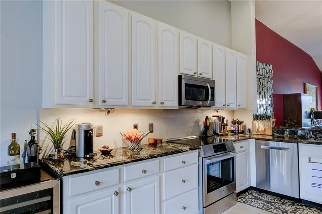 a kitchen with granite countertop a stove and white cabinets