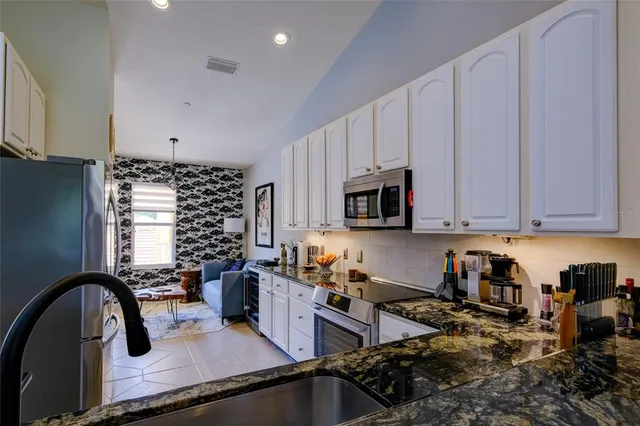 a kitchen with granite countertop white cabinets and stainless steel appliances