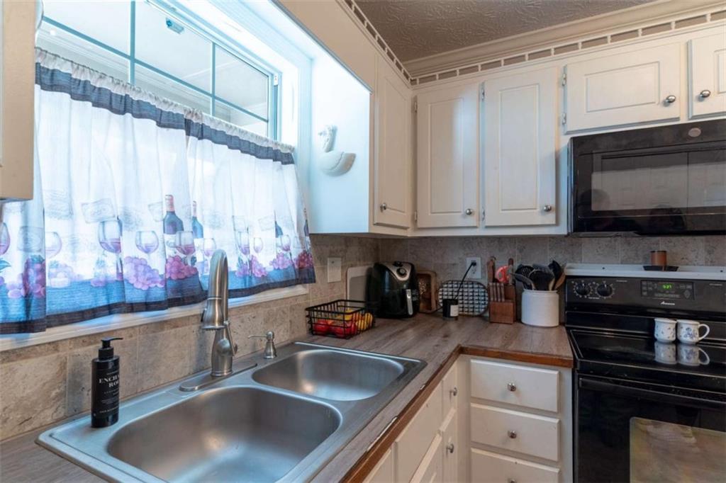 115 Woodland Ridge Circle Covington, GA 30016 - Photo 9 of 30 a kitchen with stainless steel appliances granite countertop a sink a stove and a microwave oven