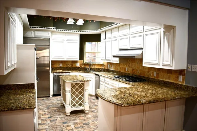 a kitchen with kitchen island granite countertop a sink appliances cabinets and a counter top space