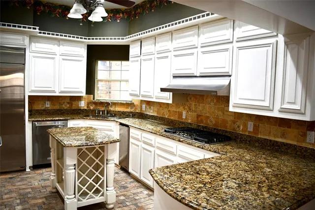 a kitchen with stainless steel appliances granite countertop a stove a sink and a microwave
