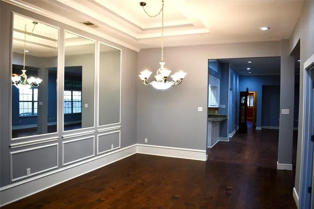 a view of an empty room with kitchen and wooden floor