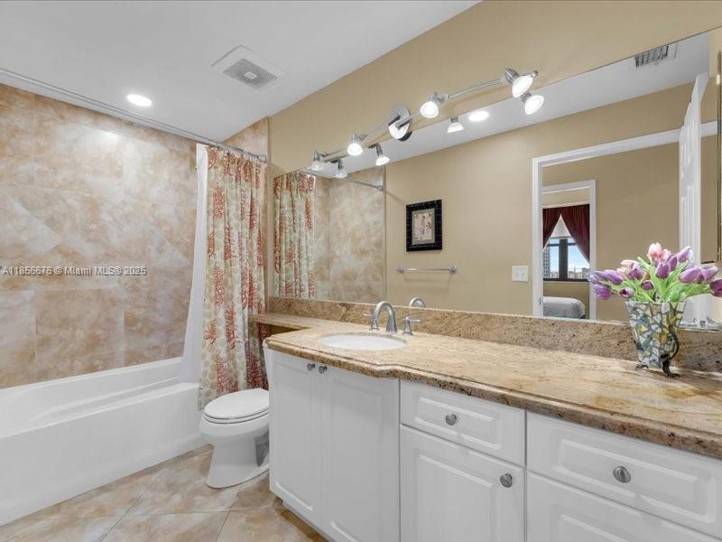 651 Okeechobee Boulevard, Unit 1002 West Palm Beach, FL 33401 - Photo 14 of 22 a bathroom with a granite countertop sink a toilet a mirror and bathtub