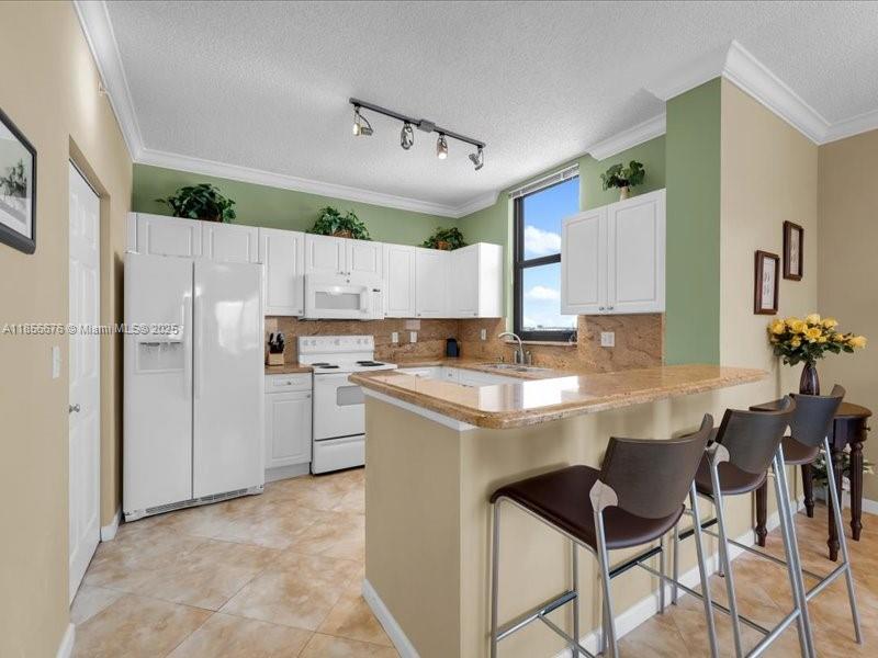 651 Okeechobee Boulevard, Unit 1002 West Palm Beach, FL 33401 - Photo 9 of 22 a kitchen with kitchen island a counter top space a sink stainless steel appliances and cabinets