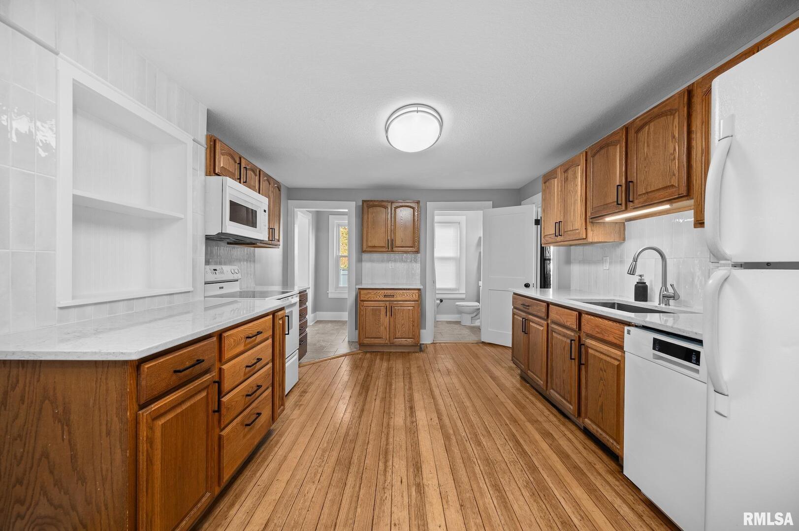 118 South 1st Street Long Grove, IA 52756 - Photo 3 of 41 a kitchen with stainless steel appliances granite countertop a sink and wooden cabinets