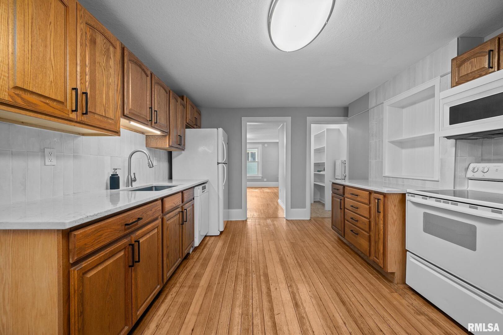 118 South 1st Street Long Grove, IA 52756 - Photo 4 of 41 a kitchen with stainless steel appliances granite countertop a stove a sink dishwasher and a refrigerator with wooden cabinets