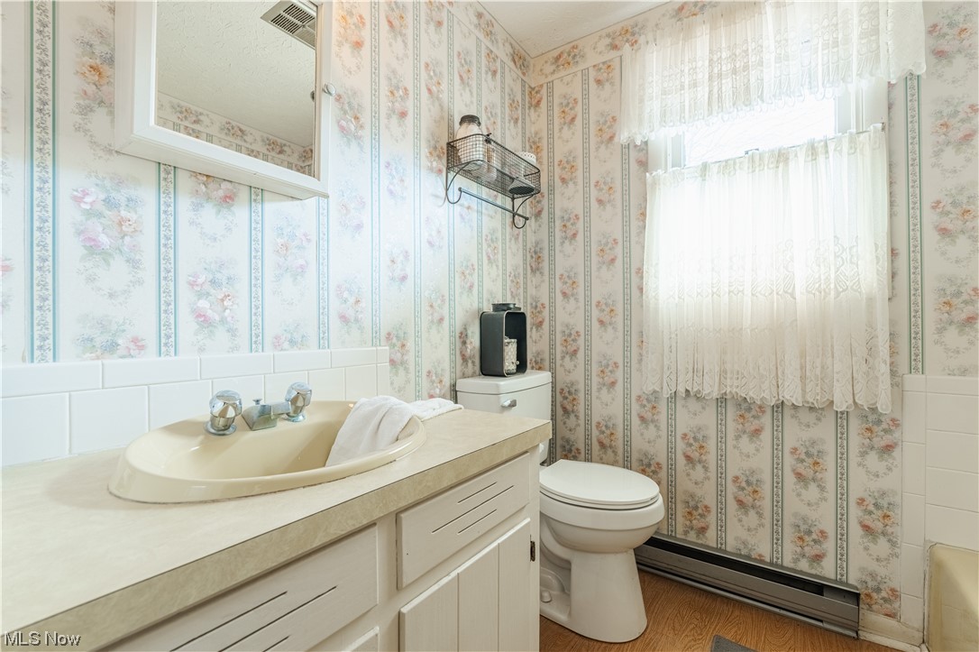 10450 Gavers Road Hanoverton, OH 44423 - Photo 26 of 50 Full bathroom featuring hardwood / wood-style floors, toilet, shower / bathtub combination with curtain, oversized vanity, and baseboard heating