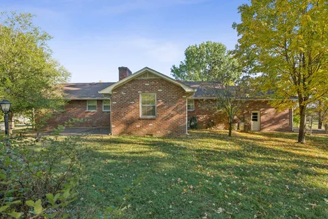 a view of a yard in front of a house with a large tree