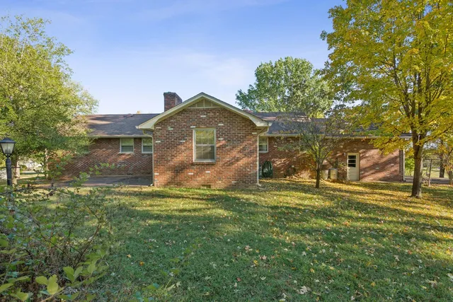 a view of a yard in front of a house with a large tree