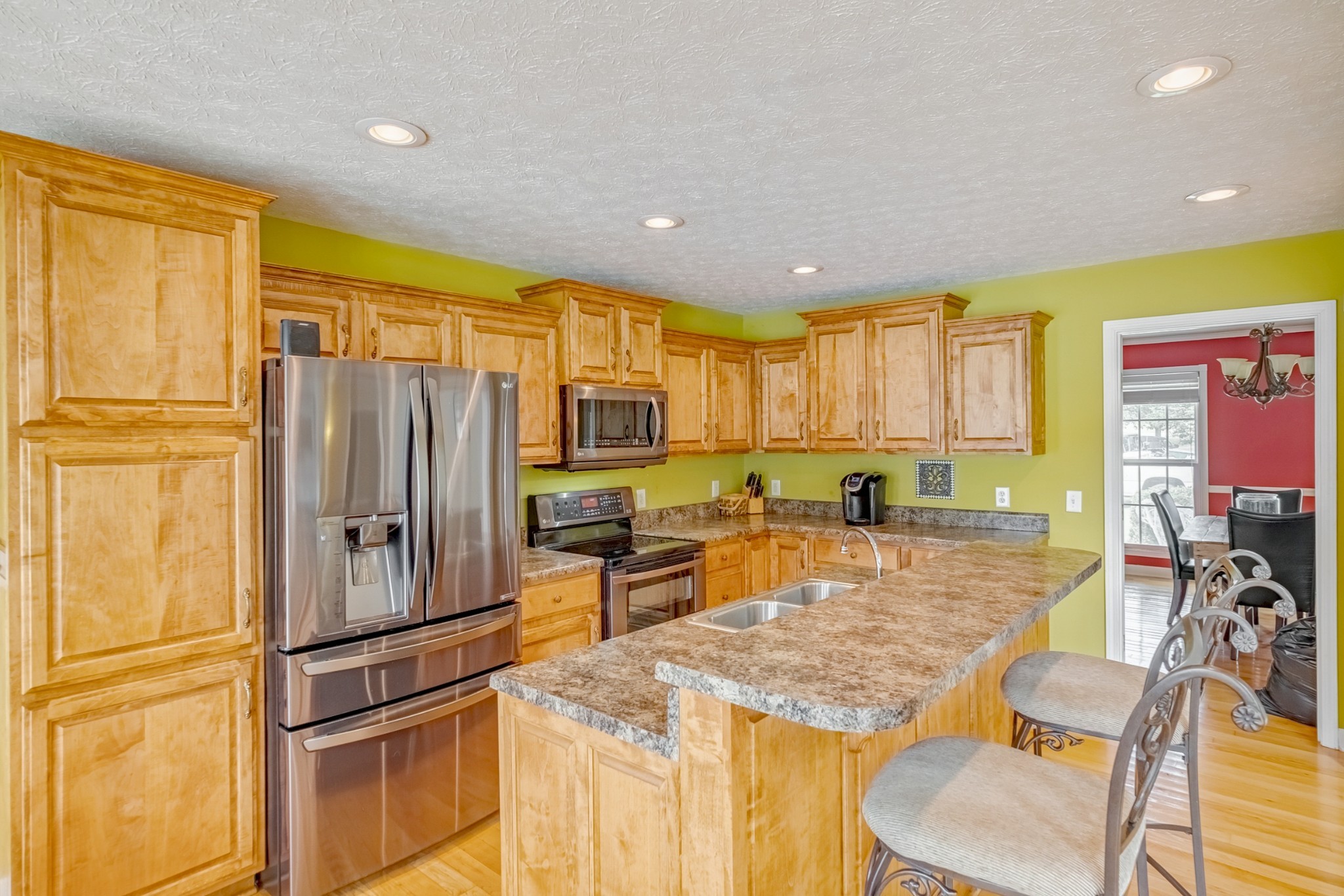 1043 Emerald Way Castalian Springs, TN 37031 - Photo 19 of 45 a kitchen with stainless steel appliances granite countertop a refrigerator a stove a sink dishwasher a dining table and chairs with wooden floor