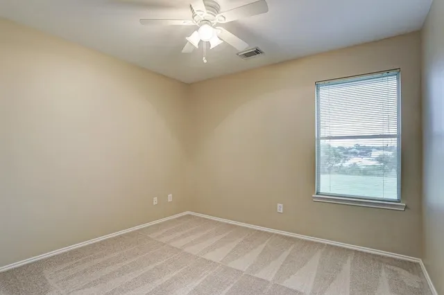 an empty room with a window and a fan