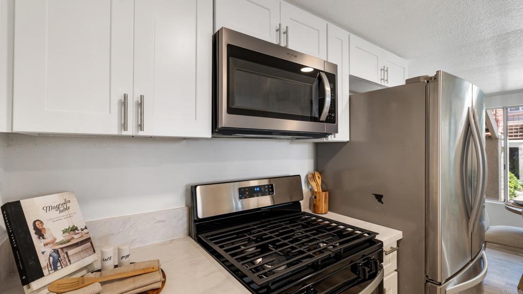415 Stoney Point Way, Unit 106 Oceanside, CA 92058 - Photo 13 of 35 a kitchen with stainless steel appliances granite countertop a stove and a microwave