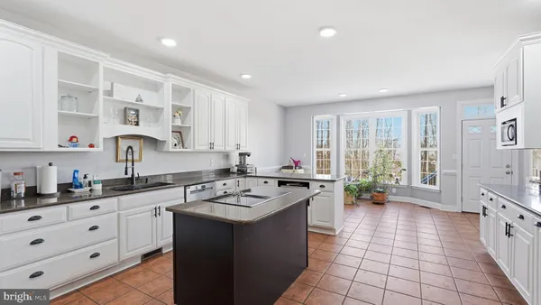 a kitchen with stainless steel appliances granite countertop a stove top oven a sink a refrigerator and white cabinets