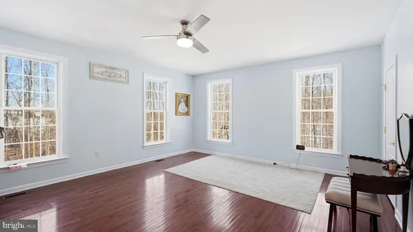 an empty room with a chandelier fan and windows