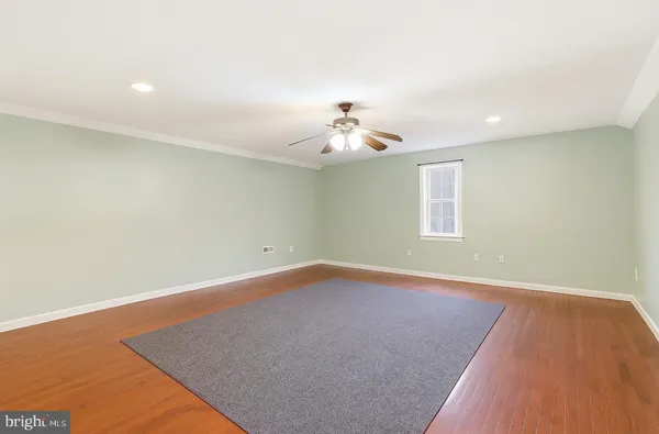 an empty room with a chandelier fan and wooden floor