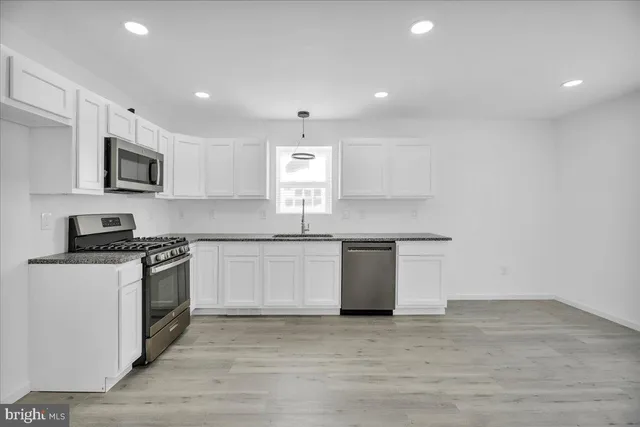 a kitchen with stainless steel appliances granite countertop a stove a sink and a microwave