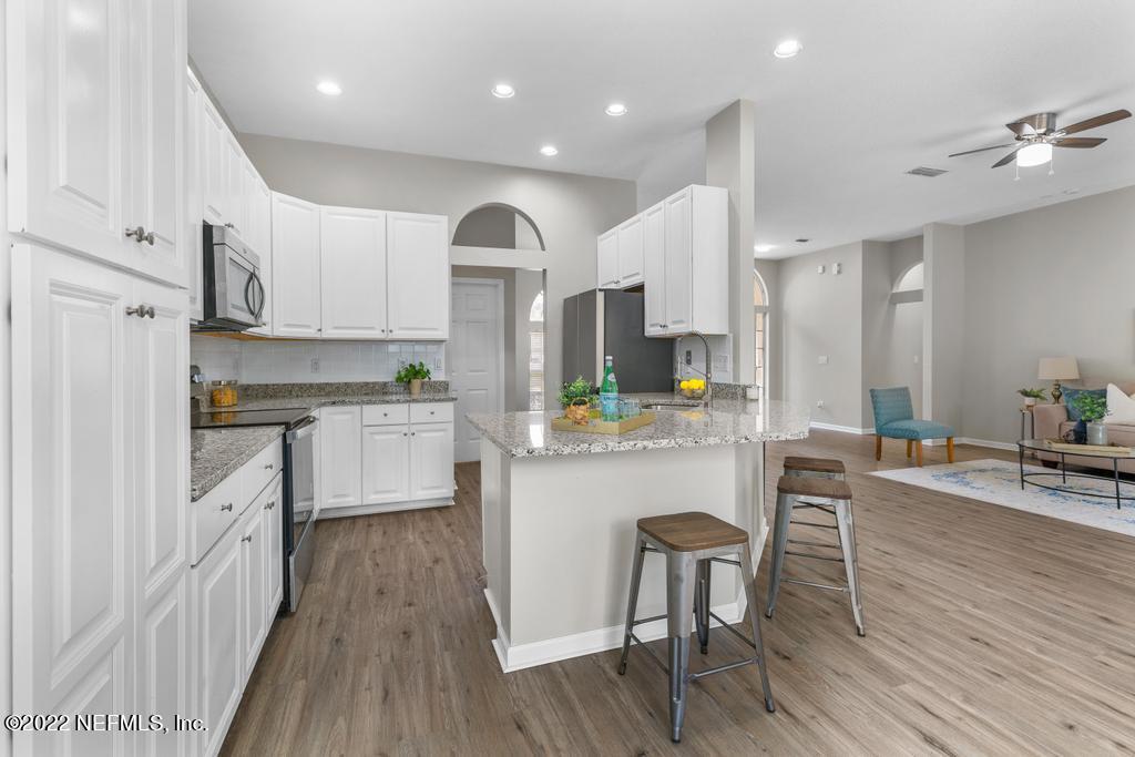 1229 Paradise Pond Road St. Augustine, FL 32092 - Photo 6 of 23 a kitchen with kitchen island granite countertop wooden floors and white cabinets